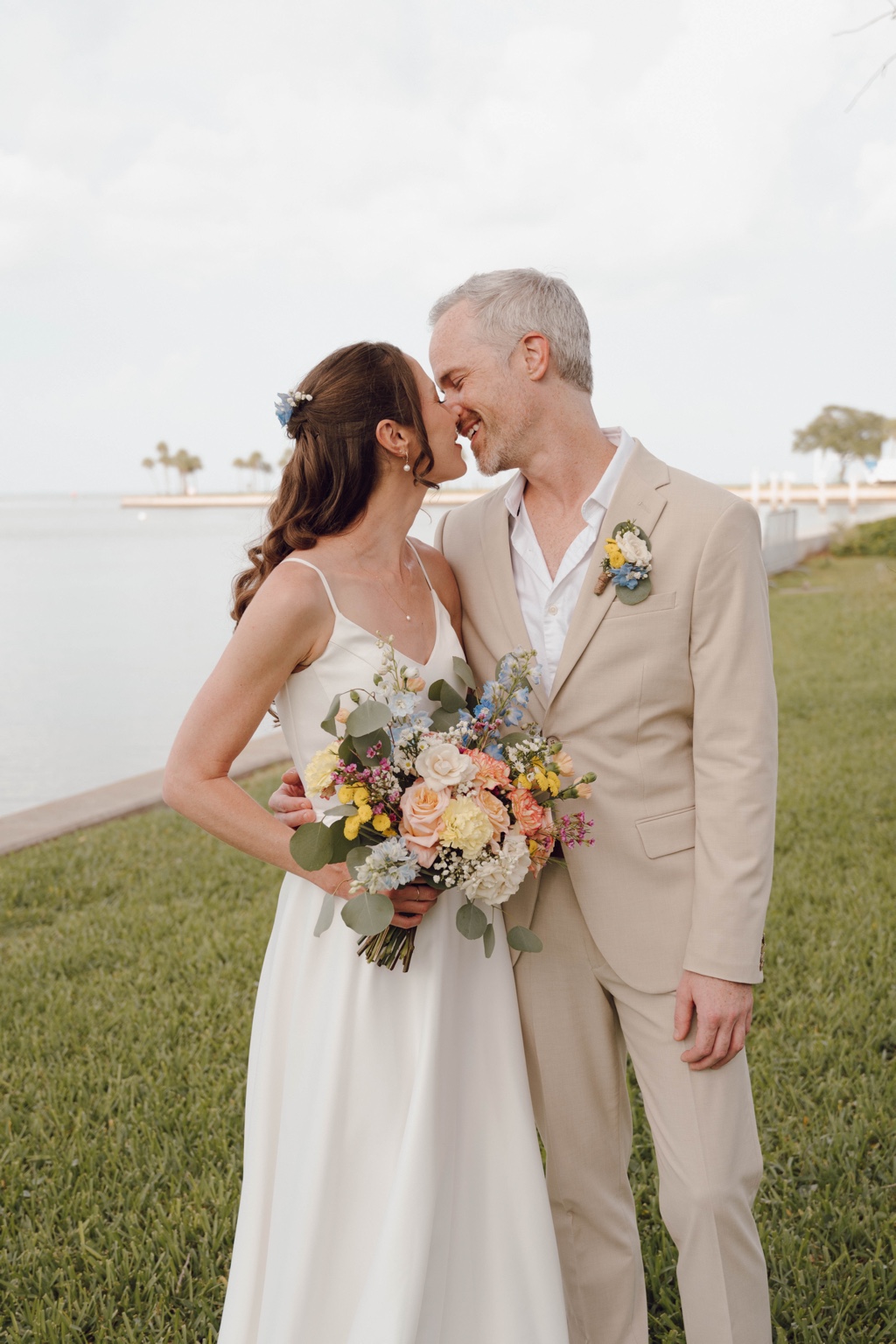 Newlyweds kissing beside the water