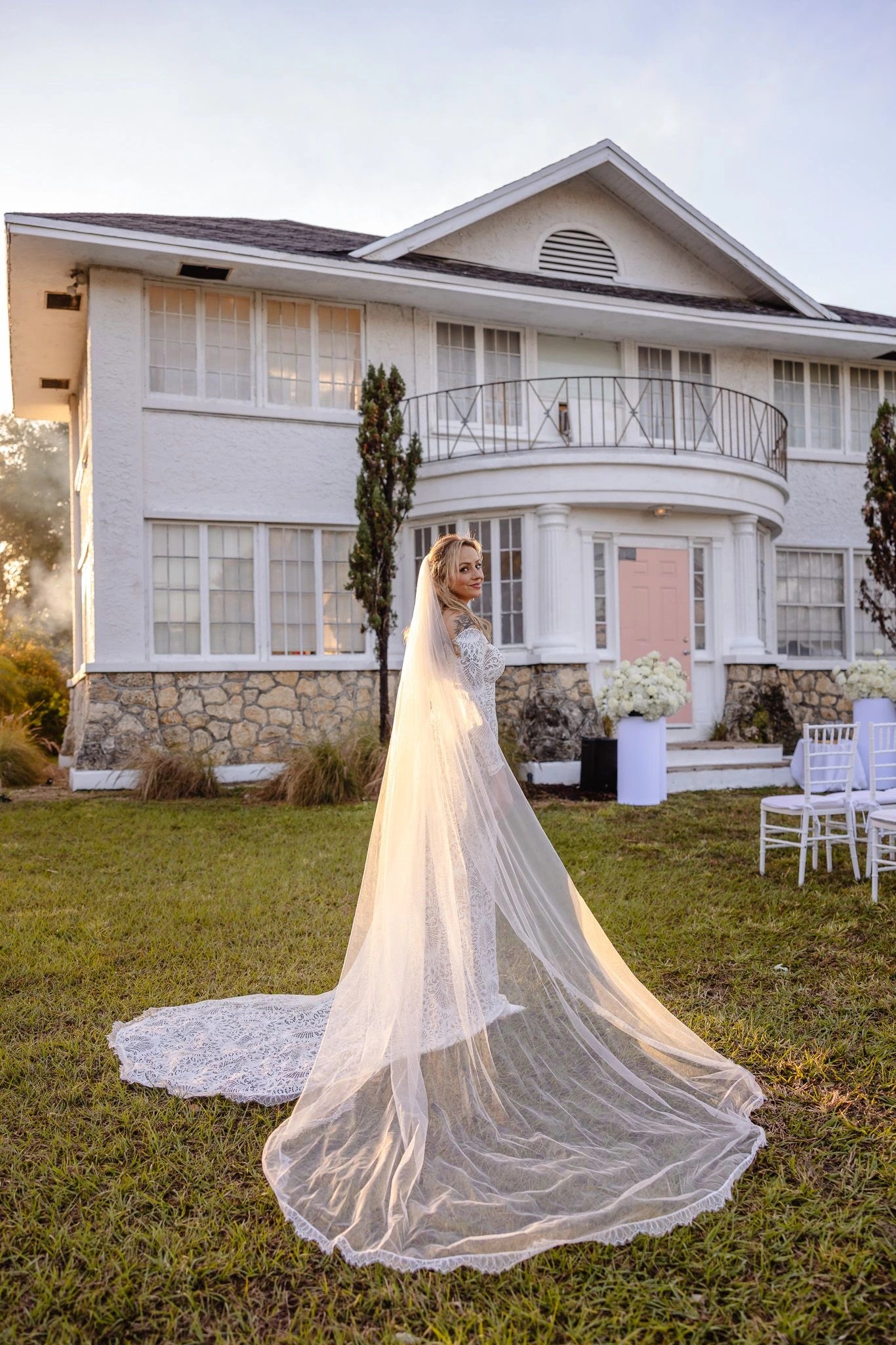 Bride in her veil outside a white coastal home