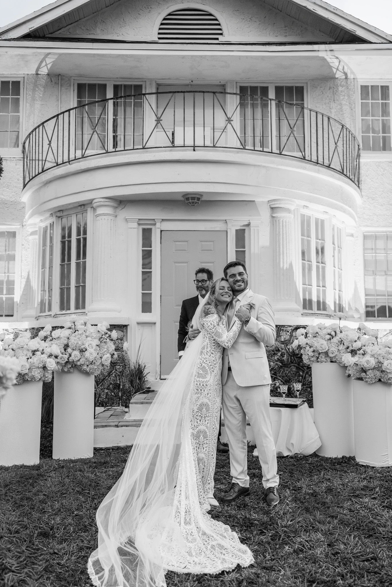 Newlyweds embracing in front of a historic white home